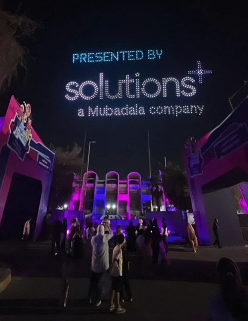 Entrance scene at night with "Presented by Solutions" signage and attendees walking in.